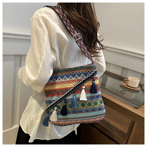 Détail du sac bohème tissé avec motifs géométriques colorés et pompons décoratifs