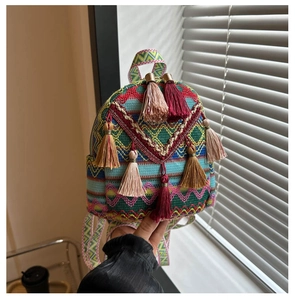Detail of colorful bohemian woven backpack featuring ethnic patterns and tassel charms