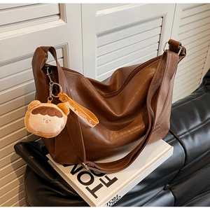 Detailed macro view of brown faux leather bag with metal zipper and plush bear charm