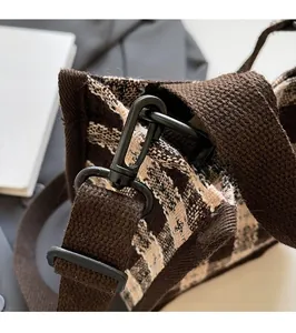 Detail of sturdy black metal shoulder strap hook on a brown checkered woven tote bag