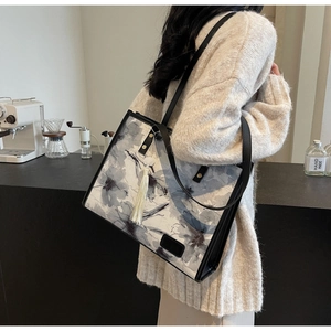 Détail d'un cabas à imprimé floral avec gland blanc et fine bandoulière noire