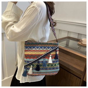 Détail d'un sac bohème tissé avec glands colorés et large bandoulière à motifs
