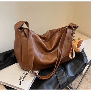 Detail of a dark brown vintage PU leather hobo bag with zipper and cute bread charm