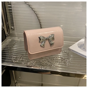 Détail du mini sac rose brillant avec un grand nœud en métal argenté et une chaîne