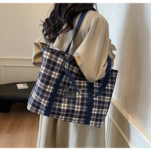 Détail du sac cabas à carreaux avec étiquette 'FASHION' noire et anses bleues