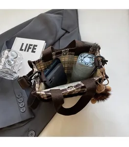 Spacious interior of brown knit checkered tote bag holding phone and folding umbrella
