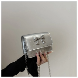 Détail d'un mini sac bandoulière argenté avec fini métallique et décoration de nœud