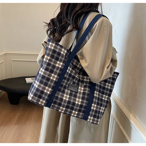 Détail du sac cabas à carreaux avec anses bleues et étiquette mode sur modèle