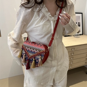 Ethnic heart-shaped woven crossbody bag with colorful tassels and red leather strap