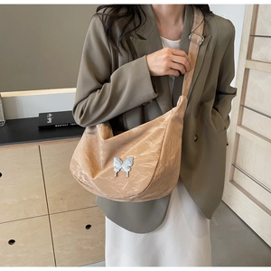 Détail du sac hobo avec ornement papillon argenté et texture de tissu plissé