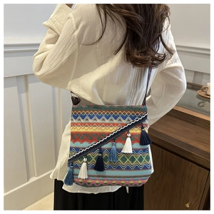 Détail d'un sac bohème tissé avec motifs ethniques et pompons colorés