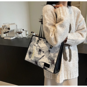 Détail d'un grand sac cabas avec motifs floraux à l'encre, finitions cuir noir et pompons