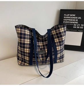 Gros plan détaillé du sac fourre-tout en toile à carreaux avec étiquette et anses tissées