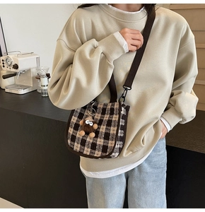 Detail of checkered crossbody bag with adjustable strap and cute plush pendant charm