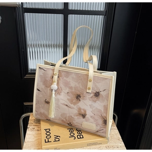 Détail du sac cabas en toile avec motifs floraux marrons et breloque lotus blanc