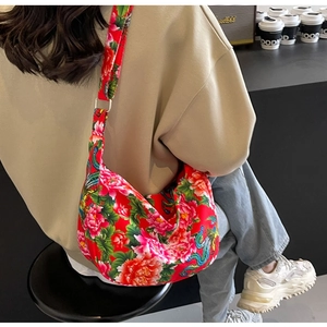 Detail of red floral tote bag with peony and phoenix embroidery in a modern cafe setting