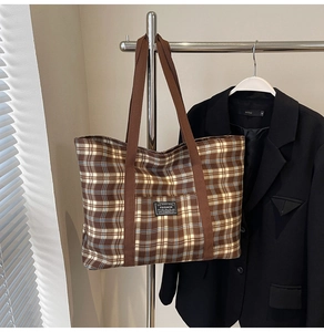 Détail du sac cabas en toile à carreaux avec lanières brunes et étiquette Fashion