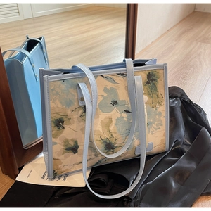 Détail d'un sac cabas à imprimé floral posé contre un miroir de plain-pied