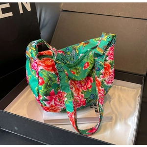 Detailed shot of emerald green satin tote bag with red peony and peacock embroidery