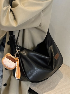 Large black minimalist tote bag with leather texture and cute plush toast keychain accessory