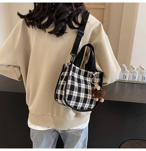 Close-up of black and white checkered tote bag with a cute brown plush bear charm