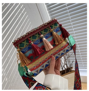 Detail view of ethnic canvas crossbody bag with bohemian tassels and woven patterns