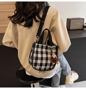 Detail of checkered canvas bag with plush monster charm and adjustable strap