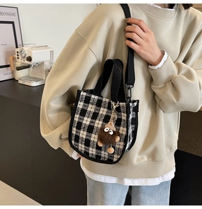 Detail of checkered crossbody bag with fuzzy monster pendant in a modern cafe setting