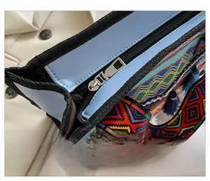 Detail of smooth metal zipper and bohemian woven strap with fringe on tote bag