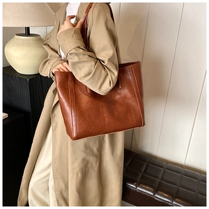 Detailed view of the brown oil wax leather texture and stitching on large tote bag
