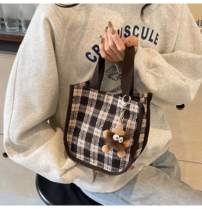 Detail of checkered tote bag with a cute brown plush monster charm and knitted hat