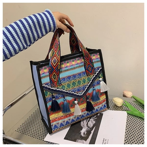 Close-up of woven ethnic tote bag with colorful geometric patterns and tassel details
