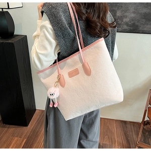 Detailed view of pink embossed faux leather tote bag featuring a cute plush pendant