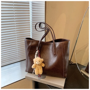 Detail of dark brown tote bag with vintage texture and cute teddy bear charm
