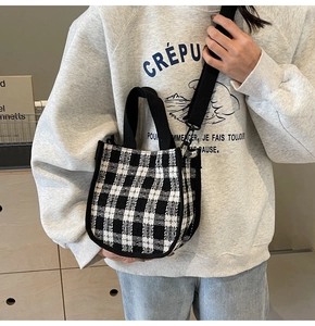 Detailed view of black and white plaid crossbody bag with fabric texture and wide strap