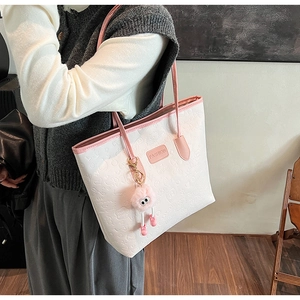 Detail of white tote bag with pink trim, cartoon embossing and cute plush charm