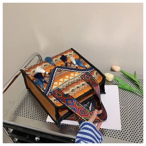 Close-up of bohemian tote bag with woven texture, blue tassels and geometric straps