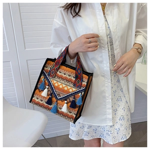 Detail of woven bohemian tote bag with ethnic patterns and colorful tassel charms