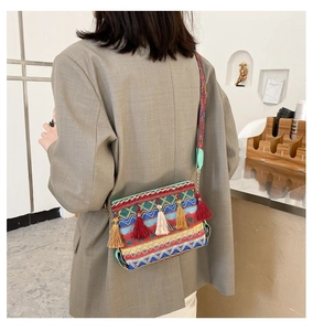 Close-up of bohemian woven crossbody bag with colorful tassels and embroidered strap