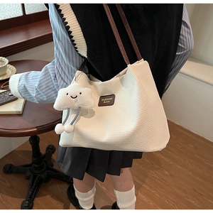 Dettaglio della borsa tote in velluto a coste bianco crema con tracolla in pelle marrone