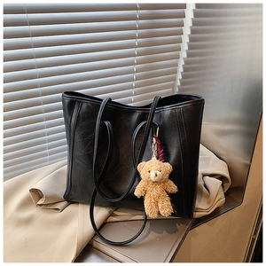 Detail of black large tote bag with wrinkled leather texture and plush bear pendant