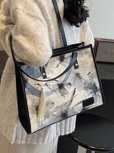 Grand sac cabas avec imprimé floral gris et anses en cuir noir porté à l'épaule