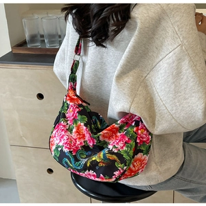 Detail of crossbody bag with red floral phoenix pattern on a black canvas texture