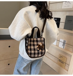 Detailed back view of a plaid tote bag with brown straps and plush bear charm