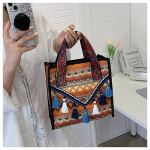 Detail of colorful woven tote bag featuring ethnic geometric patterns and stylish blue tassels