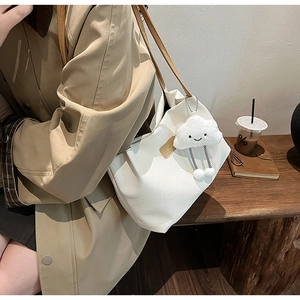 Dettaglio borsa tote bianca a nido d'ape con tracolla in pelle marrone e charm nuvola