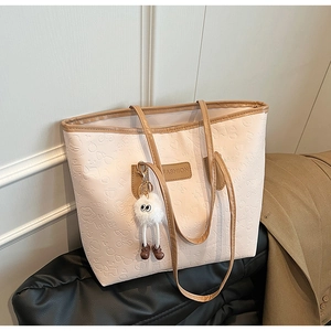 Detail of light pink tote bag with cartoon embossed patterns and brown leather strap