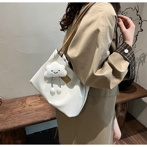 Dettaglio della borsa tote in velluto bianco con manici in pelle e ciondolo nuvola
