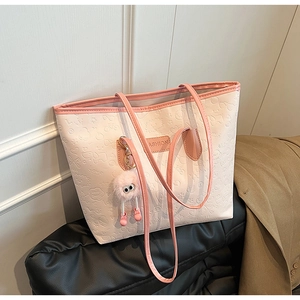 Close-up of pink embossed leather tote bag with a plush charm and fashion label
