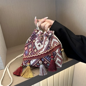 Ethnic style geometric jacquard drawstring bucket bag with colorful tassels on wood stand